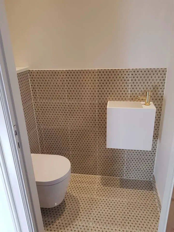 Nyrenoveret gæstetoilet med mønstrede fliser og væghængt toilet